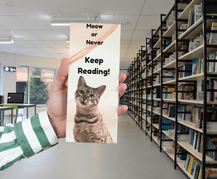Printable Whiskered Cat Bookmark held in a hand in a library setting