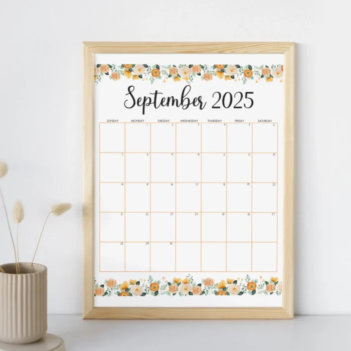 Framed printable September 2025 calendar with elegant orange floral design, displayed on a white wall